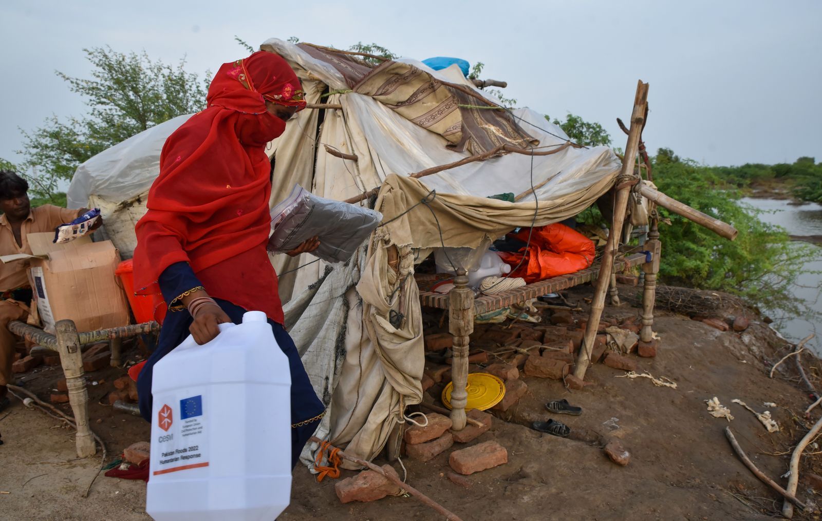 A woman whose home was destroyed by this year's devastating floods in Pakistan makes do with a shelter made of sticks and cloths and other basic items