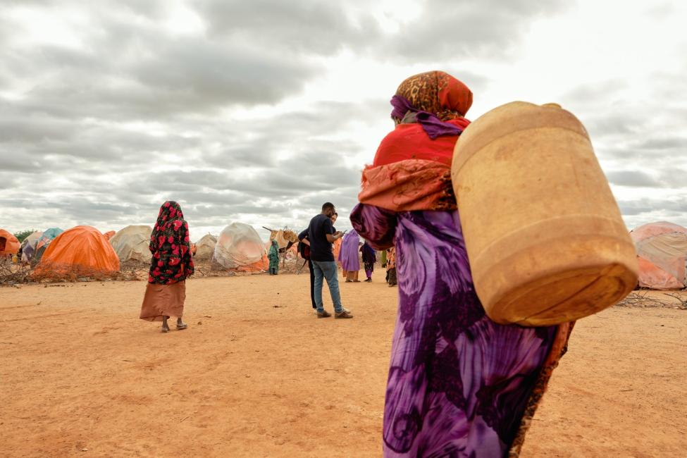 An elderly woman carries water in an informal settlement hosting thousands of people mostly displaced by drought in Somalia