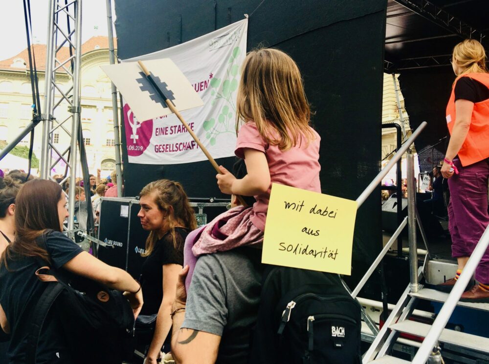 A young demonstrator on her father's shoulders expresses "solidarity" in Bern. 