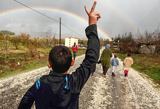 A 13-year-old boy who fled Syria flashes a victory sign by a refugee camp near Turkey's Syrian border.